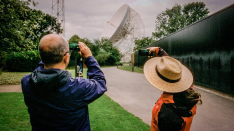 A man taking a photograph of Jodrell Bank.